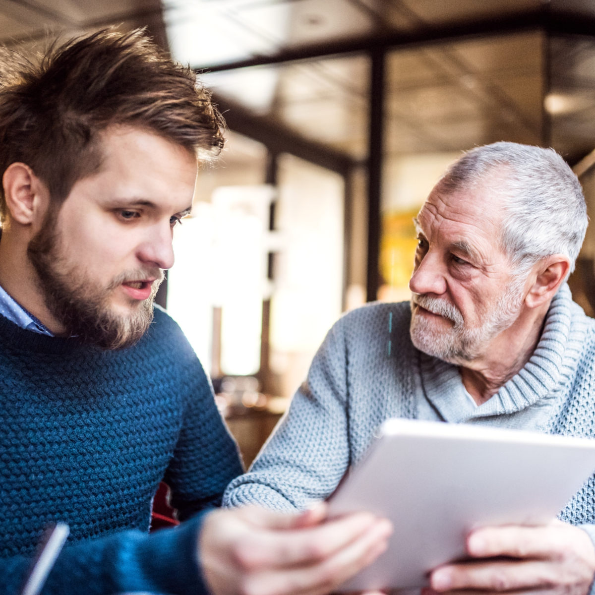 Senior father and his young son with tablet in a cafe.