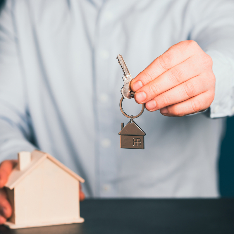 Businessman holding wooden house model and house key.Real estate, home loan and insurance concept.
